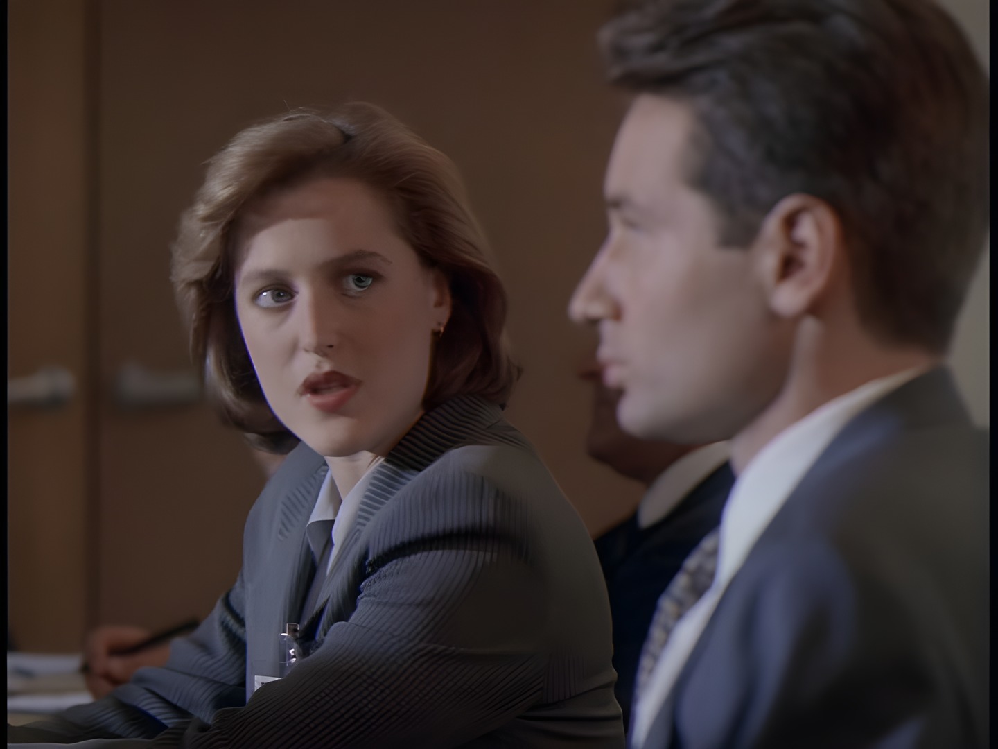 Scully and Mulder seated in profile during the briefing
