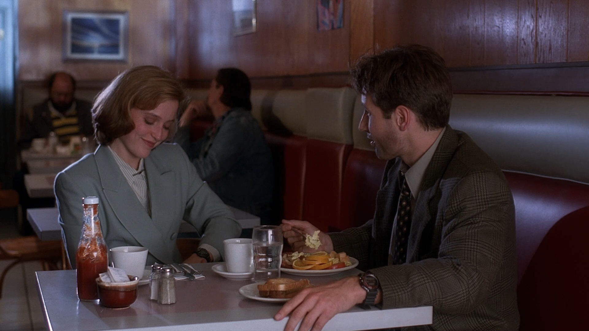 Mulder and Scully talking across a diner booth